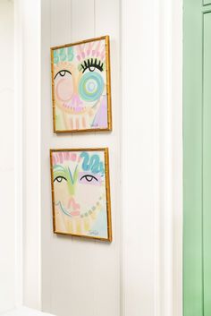 two paintings hang on the wall above a sink in a room with white walls and green cabinets