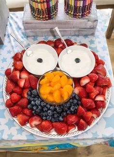 a plate with strawberries, blueberries, oranges and yogurt on it