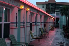 several chairs are lined up on the side of a building with lights in front of them