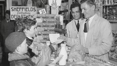 black and white photograph of three men in a store with boxes of milk on the counter