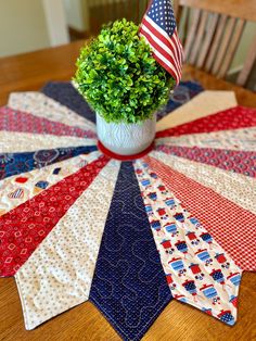 a potted plant sitting on top of a wooden table next to an american flag quilt