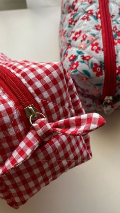 two red and white checkered bags sitting on top of a table next to each other