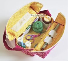 an open sewing case with yarn, scissors and other crafting supplies in it on a white surface