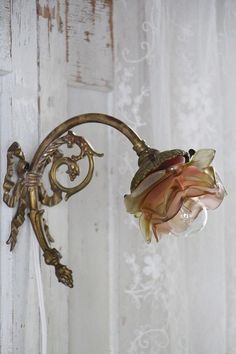 a flower is hanging on the wall next to a light fixture in an old - fashioned room