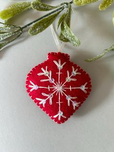 a red ornament with white snowflakes hanging from it's side