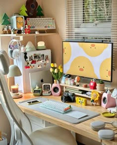 a desk with a computer monitor, keyboard and other items on it in front of a window