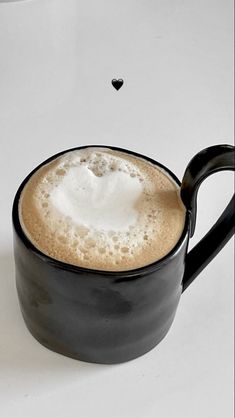 there is a cup of coffee with foam in the shape of a heart on it