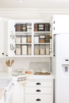 an organized kitchen with white cabinets and drawers