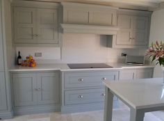 a white kitchen with gray cabinets and counter tops, flowers in vase on the table