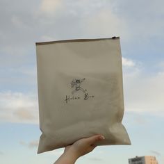 a person holding up a bag with a drawing on it in front of some buildings