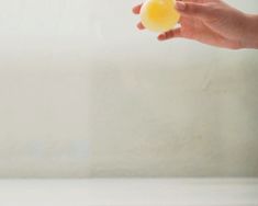 a person holding an orange in their left hand, with the other hand reaching for it