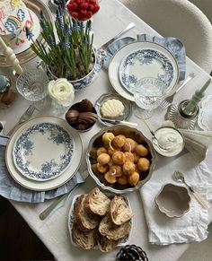 a table topped with plates and bowls filled with food on top of a white table cloth