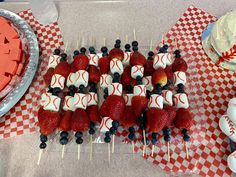 strawberries and blueberries are arranged on sticks in the shape of baseballs, bats and balls