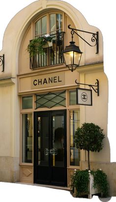 a chanel store front with plants and lights on the outside wall, along with potted trees