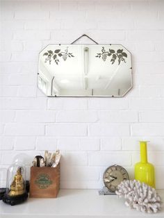 a white brick wall with a mirror and other items on the shelf next to it