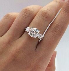 a woman's hand with a diamond ring on top of her finger and an engagement band