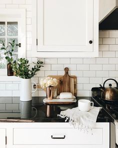 a vase with flowers sitting on top of a kitchen counter