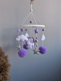 a purple and white mobile with stars hanging from it's sides on a wall