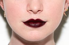 a close up shot of a woman's face with red lipstick and nose piercings