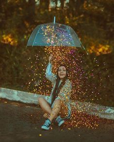 a woman sitting on the ground under an umbrella covered in confetti and sprinkles