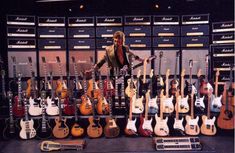 a man standing in front of a display of guitars