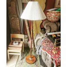 a lamp sitting on top of a wooden floor next to a chair and table in a living room