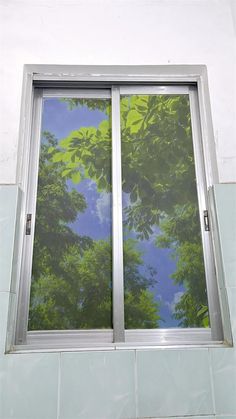 an open window with trees reflected in it's windowsills and the sky