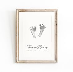 a baby's hand and foot prints are displayed in a frame on the wall