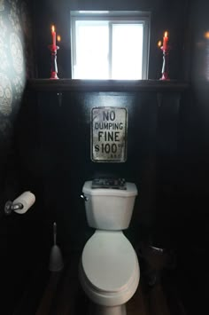 a white toilet sitting in a bathroom next to a window with no dumping fine $ 100 sign on it