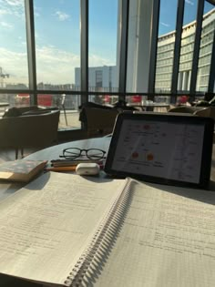 an open notebook sitting on top of a table next to a tablet computer and glasses