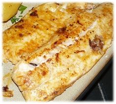 two fish fillets sitting on top of a white plate next to a yellow banana