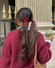 a woman in a red sweater is holding a cup and looking at her cell phone