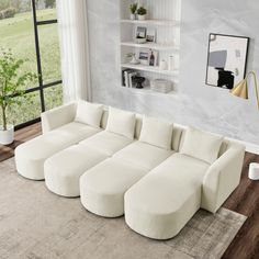 a living room with a large white sectional couch in the center and windows to the side