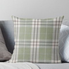 a green plaid pillow sitting on top of a couch next to two white pillows and a gray throw pillow