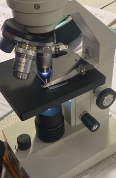 a microscope is shown with the light shining through it's glass lens and some other items