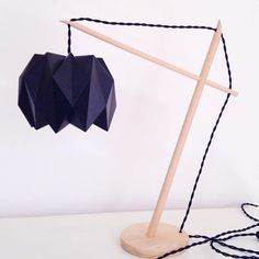 a black origami heart hanging on a clothes line next to a wooden stick