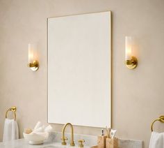 a bathroom sink with two gold faucets and a large white mirror above it