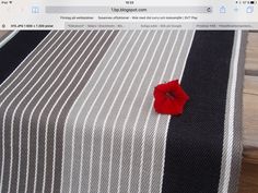 a red flower sitting on top of a black and white table cloth