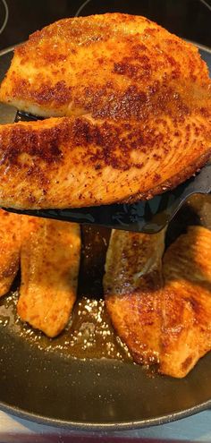 two pieces of fish are being cooked in a frying pan