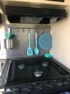 a stove top oven sitting inside of a kitchen next to pots and utensils