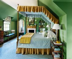 a bedroom with green walls and yellow drapes on the canopy bed, along with a fireplace