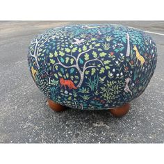 a foot stool with an animal and tree design on it's top, sitting in the middle of a street