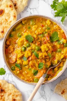 a bowl of vegetable curry with pita bread on the side