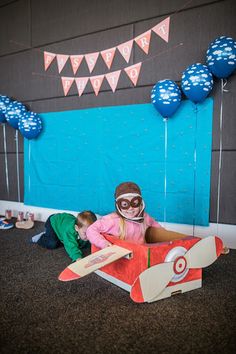 two children are playing in a cardboard airplane