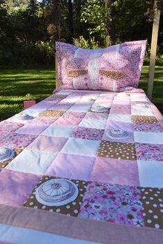 a bed with pink and brown bedspread on it in the middle of some grass