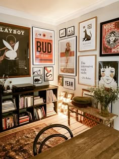 a room with posters on the wall and a wooden table in front of an area rug