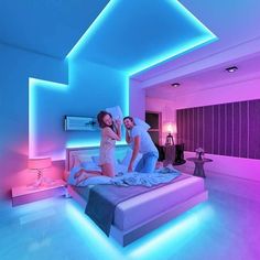 two people standing on a bed in a room with blue and pink lighting around them