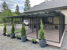 a dog kennel in front of a house with potted plants