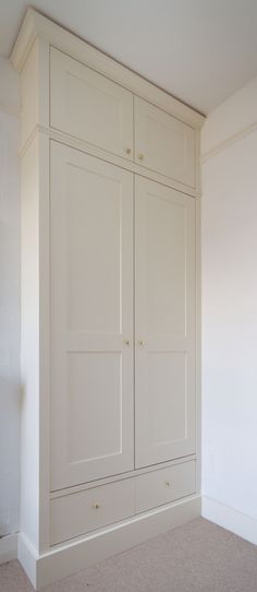 an empty room with white cupboards and carpeted flooring on the side wall