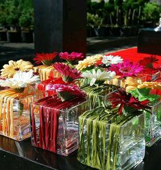 there are many different colored vases with flowers in them on the black table outside